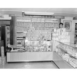 Staff member with Nolan's Pharmacy Baby Products display, corner of Brisbane and Nicholas Streets, Ipswich, 1955